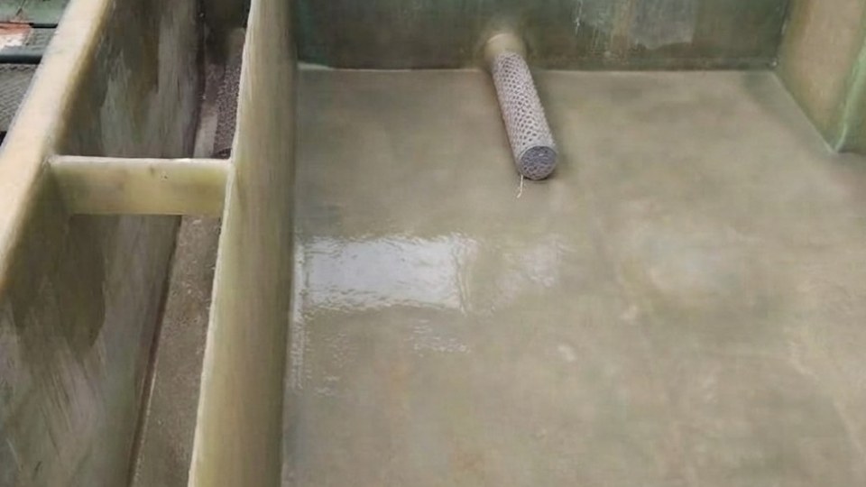 Large fiberglass resin tank under construction in a fabrication shed