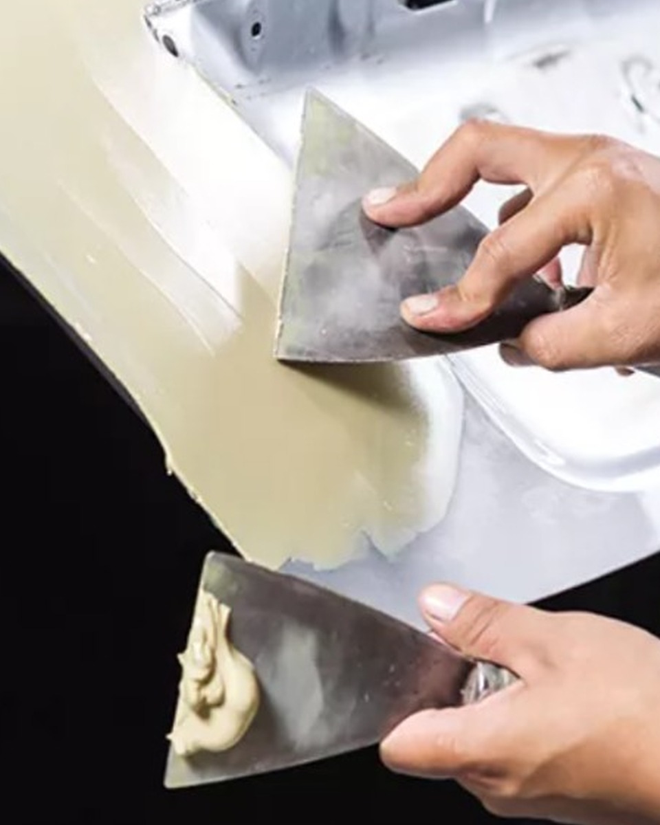 Applying flexible putty resin with putty knives on auto body panel